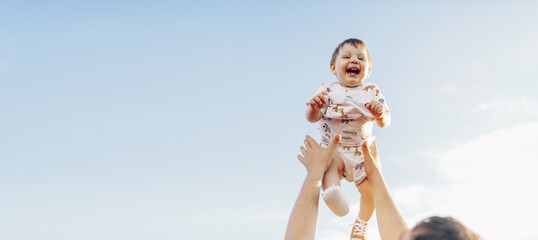 The father plays with the small child, the son, throws him up to the sky. Summer