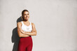 Strong fitness woman exercise on fresh air. Sportswoman smiling after good workout, training outdoors in sport leggings and crop top, cross arms on chest determined, standing against concrete wall