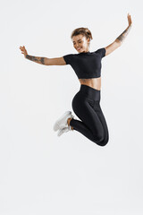 Female fitness girl jumping, freeze in air silhouette of young woman runner, athlete smiling and posing free, wearing sportswear outfit for workout on white background