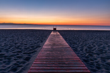 Wall Mural - a wooden, red footbridge leading to the sea