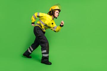 Poster - Full length photo of serious purposeful young firewoman dressed yellow uniform walking sneaking isolated green color background