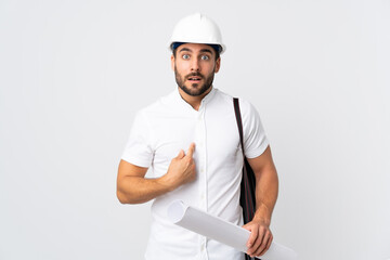 Sticker - Young architect man with helmet and holding blueprints isolated on white background pointing to oneself