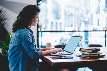 Skilled freelancer checking received information on modern laptop computer with blank screen, Caucasian female student preparing to university exams while e learning on netbook in coworking space