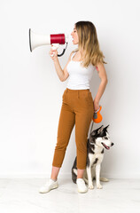 A full length young pretty woman with her dog shouting through a megaphone