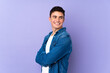 © luismolinero - Teenager caucasian  handsome man isolated on purple background with arms crossed and happy