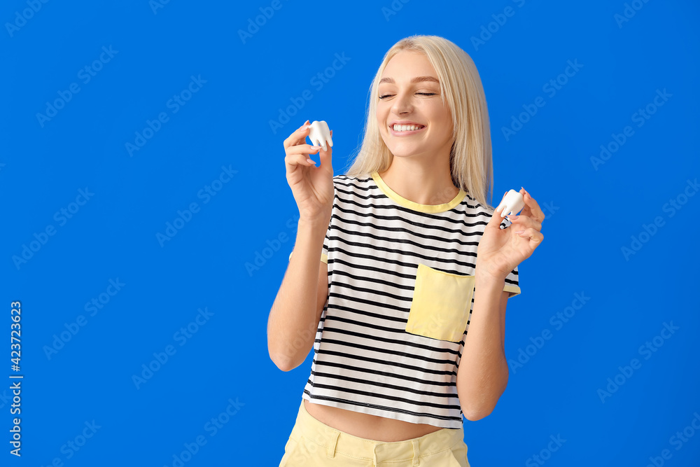 Beautiful young woman with plastic teeth on color background