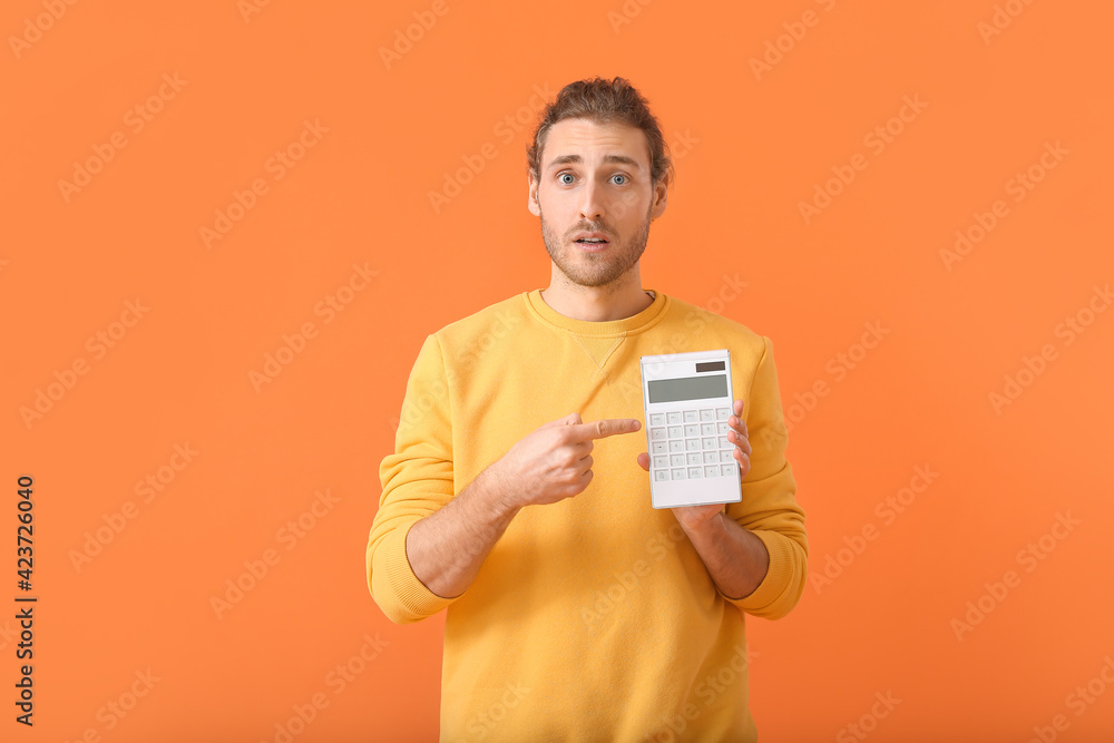 Shocked man with calculator on color background