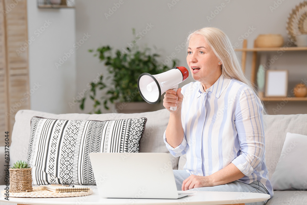Screaming mature woman with megaphone at home
