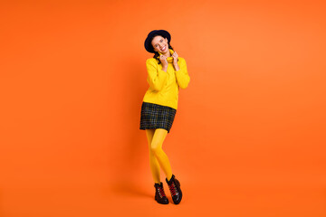 Wall Mural - Full size photo of optimistic funky girl wear yellow sweater cap skirt shoes isolated on orange background