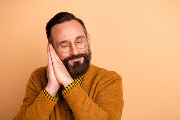 Poster - Photo of sleepy mature man sleep with hands under face isolated over beige color background