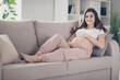 © deagreez - Full length photo of pretty happy young woman mother touch belly lie sofa in living room indoors inside house