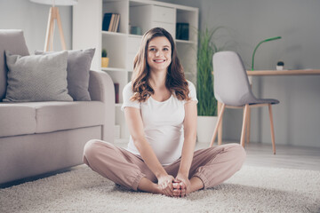 Sticker - Full size photo of charming cheerful girl sit on carpet hands hold touch foot together beaming smile home indoors