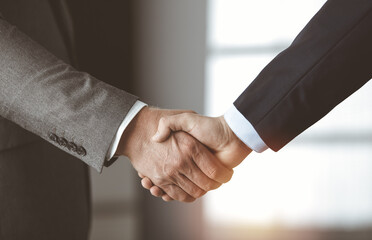 Business people standing and shaking hands in sunny office, close-up. Handshake and marketing