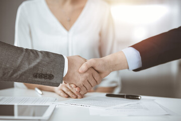 Business people shaking hands finishing contract signing in sunny office, close-up. Handshake and marketing