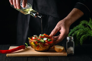 Cook pours olive oil into a bowl of salad. Cooking tasty and healthy food with set of vitamins