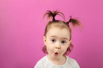 Portrait of surprised cute little girl standing on pink background. Top view