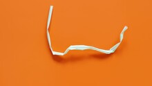 Used plastic drinking straws on the orange background top view