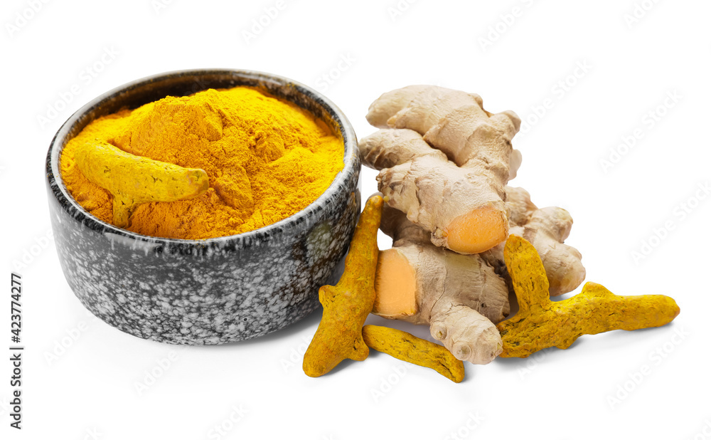 Bowl with turmeric powder and roots on white background