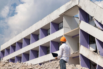 Wall Mural - Engineer holding laptop is checking for destruction, demolishing building.