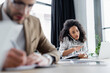 © LIGHTFIELD STUDIOS - African american businesswoman talking on smartphone and holding notebook in office