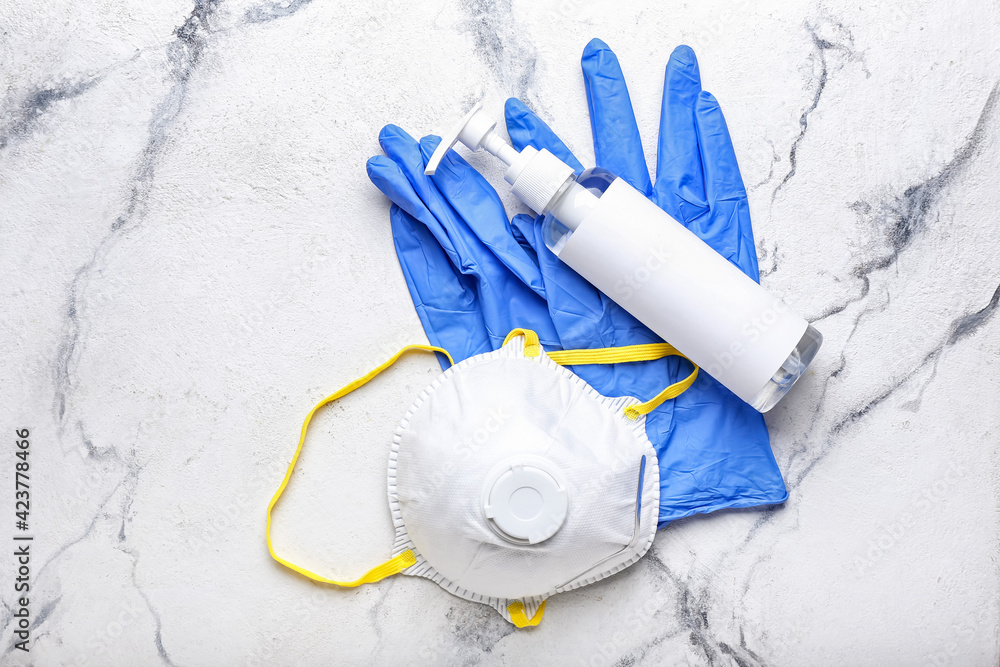 Respirator, protective gloves and antiseptic on light background