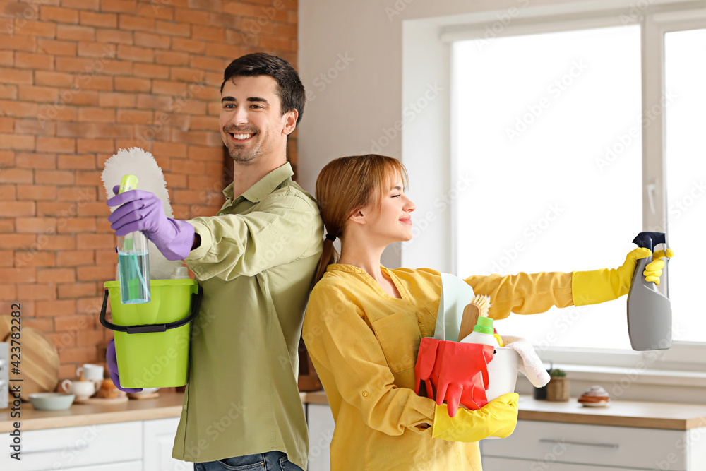 Couple with cleaning supplies in kitchen