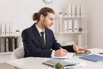 Wall Mural - Male accountant with calculator working in office