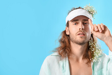 Canvas Print - Portrait of handsome young man with flowers in hair on color background