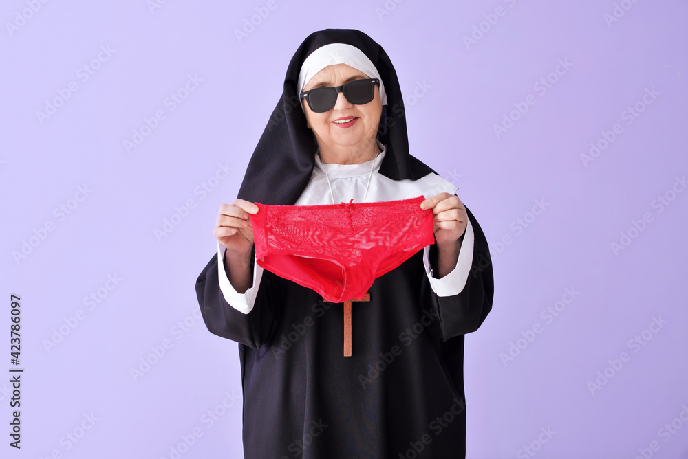 Funny senior nun with panties on color background