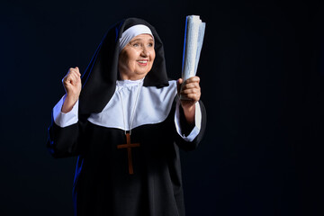 Wall Mural - Senior nun with newspaper on dark background