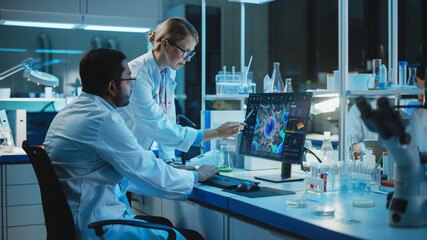 Wall Mural - female research scientist with bioengineer working on a personal computer with screen showing virus 