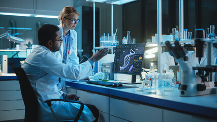 Wall Mural - female research scientist with bioengineer working on a personal computer with screen showing dna an
