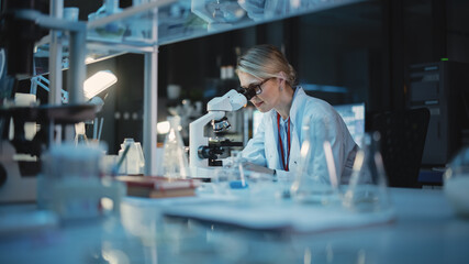 Medical Development Laboratory: Caucasian Female Scientist Looking Under Microscope, Analyzes Petri Dish Sample. Specialists Working on Medicine, Biotechnology Research in Advanced Pharma Lab