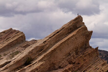 A Lone Hiker At The Top Of A Mountain Surveying The Desert. 