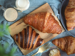 Top view of French chocolate and butter croissants with pot of milk and coffee, It is a buttery, flaky pastry. Made with a yeast leavened dough that has been laminated with butter in multiple layers