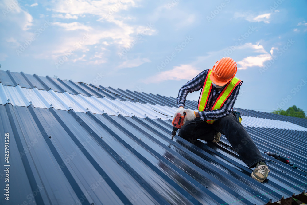 Asian Roofer worker safety wear using air or pneumatic nail gun and installing on new roof metal sheet, Roof concept of residential building under construction. - obrazy, fototapety, plakaty 