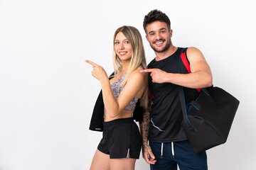 Young sport couple isolated on white background pointing finger to the side in lateral position