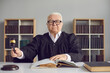 © Studio Romantic - Portrait of a stern mature judge knocking with a hammer passing sentence and announcing that the case will be closed. Man is sitting in his office or in the courtroom. Concept of human law and justice