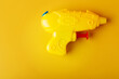 Plastic water gun on yellow background. Toy Squirt pistol.