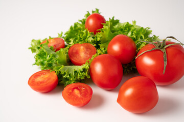 Ripe juicy cherry tomatoes and green lettuce as a concept of food vitamins and antioxidants. Half cut tomatoes