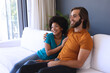 © wavebreak3 - Happy diverse couple sitting on sofa embracing and smiling