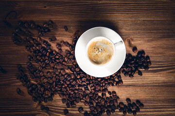 cup of coffee with coffee beans on wooden background