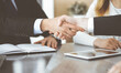© Iryna - Unknown businessmen shaking hands above the glass desk in a modern office, close-up. Unknown business people at meeting. Teamwork, partnership and handshake concept