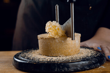 Shaving tete de moine cheese using girolle knife. Variety of Swiss semi-hard cheese made from unpasteurized cows milk, the name Monks head