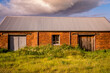 © Gary Chapman/Austockphoto - An old brick barn with a colourful cloud overhead