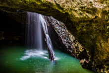 Water Flowing Through Natural Arch Into Underground Cave