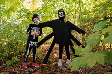 Girl (8-9) And Boy (6-7) Wearing Halloween Costumes In Forest