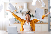 A Crazy Excited Happy Young African American Woman, Business Lady, Manager Or Freelancer Working Remotely At Home, Enjoying Career Growth Or Good Deal, Gesturing With Hands, Scattering Documents