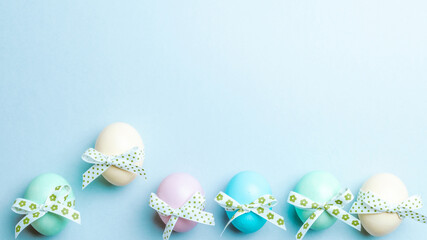 Wall Mural - Easter flat. Colorful egg with tape ribbon on pastel blue background in Happy Easter decoration. Spring holiday top view concept.