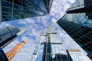 Skyscrapers, modern business office buildings in commercial district, architecture raising to the blue sky with white clouds, bottom view 